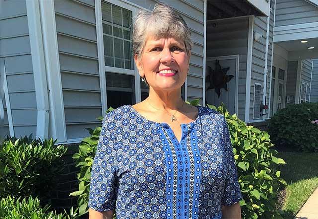 Judy standing outside house, smiling